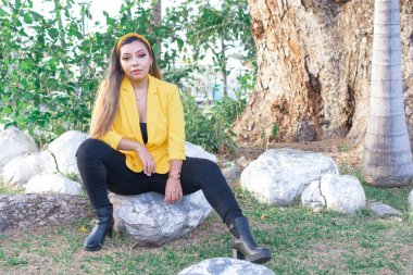 Sarı ceketli bir kadının açık hava portresi. Gün batımında bahçedeki genç Meksikalı kadının portresi..