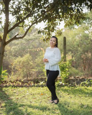 Bir kırsal kesimdeki genç bir kadının portresi. Gün batımında ellerinde sarı meyvelerle batan genç bir kadın. Tam boy portre.