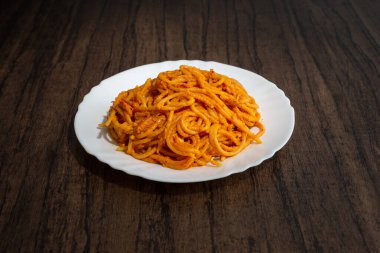 Tahta masada beyaz tabakta servis edilen spagetti tabağı. Lezzetli spagetti..