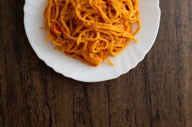 Tahta masada beyaz tabakta servis edilen spagetti tabağı. Lezzetli spagetti..