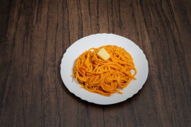 Tahta masada beyaz tabakta servis edilen spagetti tabağı. Lezzetli spagetti..