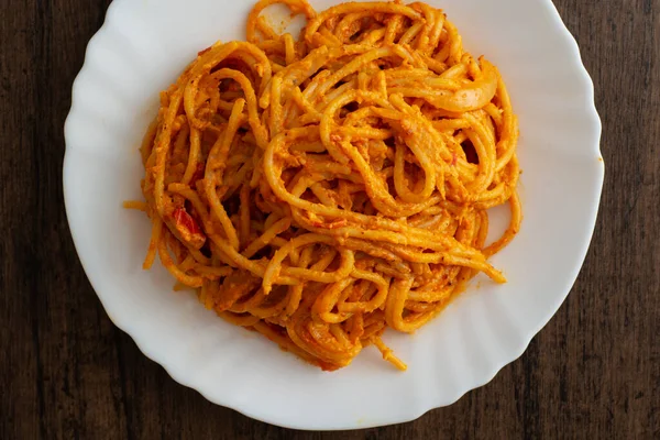 Tahta masada beyaz tabakta servis edilen spagetti tabağı. Lezzetli spagetti..