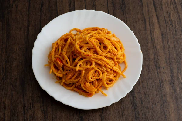 Tahta masada beyaz tabakta servis edilen spagetti tabağı. Lezzetli spagetti..