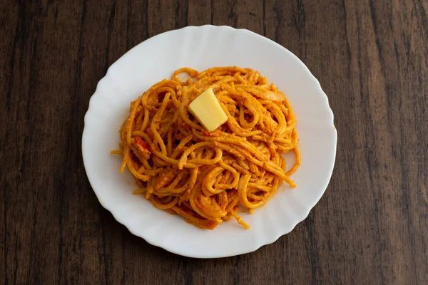 Tahta masada beyaz tabakta servis edilen spagetti tabağı. Lezzetli spagetti..