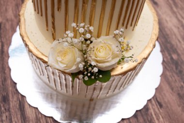 Doğal güllerle süslenmiş pasta. Ahşap masada güllerle süslenmiş güzel bir düğün pastası..