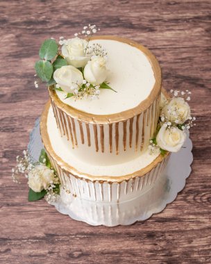 Doğal güllerle süslenmiş pasta. Ahşap masada güllerle süslenmiş güzel bir düğün pastası..