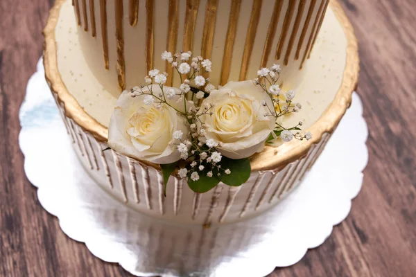 Cake decorated with natural roses. Beautiful wedding cake decorated with roses on wooden table.