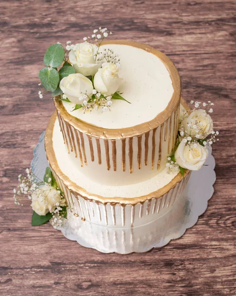 Doğal güllerle süslenmiş pasta. Ahşap masada güllerle süslenmiş güzel bir düğün pastası..