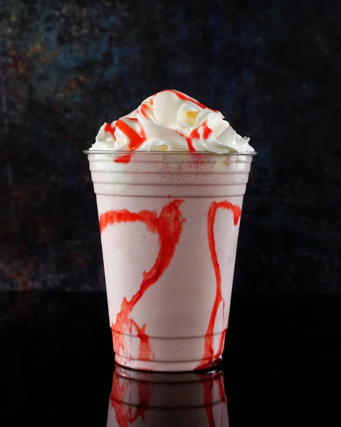Çilekli milkshake, koyu arkaplanda açık bardakta çilek şurubu..