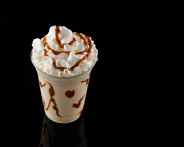 Vanilla milkshake with chocolate syrup in clear glass on dark background.