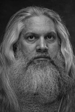 Sakallı ve uzun saçlı bir adamın siyah beyaz portresi. Yakın plan..