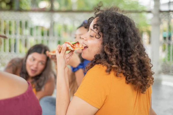 Young woman eating pizza. Young woman sitting eating mexican pizza with friends.