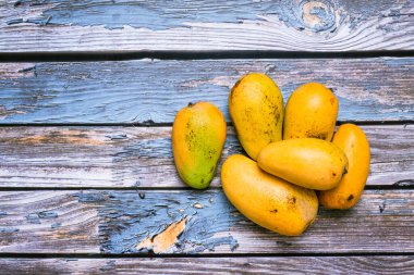 Ahşap masada, karanlık ortamda bir grup olgun mango. Üst görünüm.