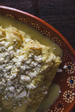 Yeşil Enchilada 'lar ahşap bir masada kil tabakta servis edilir. Tipik Meksika yemekleri..