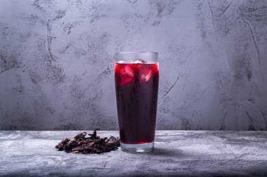 Beton masada Jamaika çiçeğiyle hazırlanmış bir içki. İçki ve Jamaika çiçeği masada..