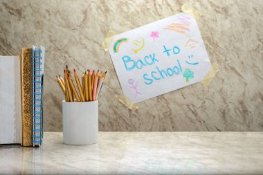 Mermer bir masanın üzerindeki bir fincanda renkli kalemler. Yazılı bir çocuk tarafından çizilen mermer arkaplan 