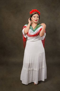 Mexican woman with white dress and tricolor scarf. Full length female portrait in studio of Mexican woman with scarf with the colors of the Mexican flag.