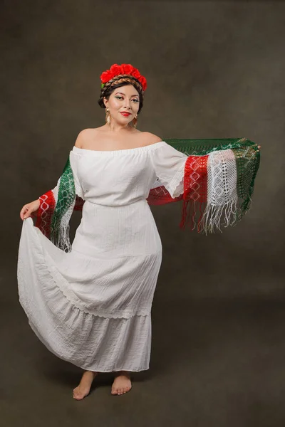 Mexican woman with white dress and tricolor scarf. Full length female portrait in studio of Mexican woman with scarf with the colors of the Mexican flag.