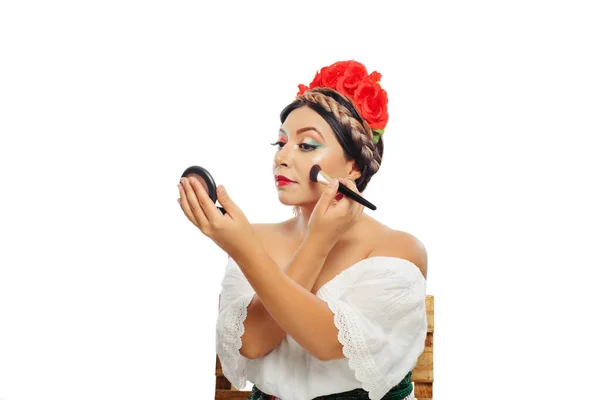 Mexican woman made up with Mexican flag colors wearing white dress. Mexican woman seated making herself up.