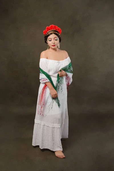 Mexican woman with white dress and tricolor scarf. Full length female portrait in studio of Mexican woman with scarf with the colors of the Mexican flag.