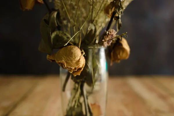 Vase with dried flowers on wooden table. Concept of autumn, loneliness, sadness.