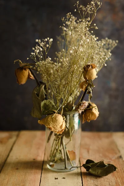 Vase with dried flowers on wooden table. Concept of autumn, loneliness, sadness.