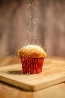Cupcake isolated on wooden table. Cupcake in red paper mold.