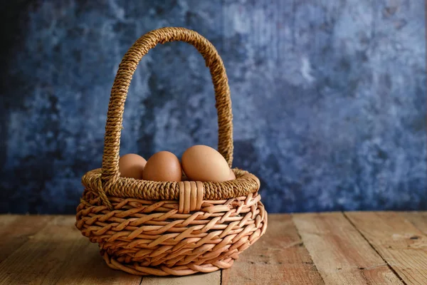 Farm fresh eggs in a wicker basket. Blue background.