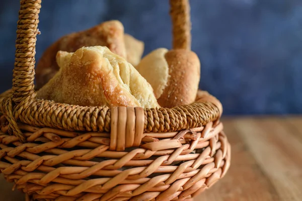 木製のテーブルの上に甘いパンとウィッカーバスケット 青の背景 — ストック写真