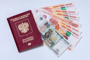 Beyaz arka planda Rusya Federasyonu pasaportu ve Rus banknotları (ruble). Rusya vatandaşlarına seyahat, ekonomik yaptırımlar, para transferleri ve enflasyon kavramları