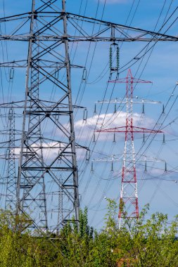 Yüksek voltajlı elektrik kabloları taşıyan üçgenleri olan metal sütunlar. Elektrik nakil şebekeleri, enerji arzı ve enerji tüketim sorunları kavramları