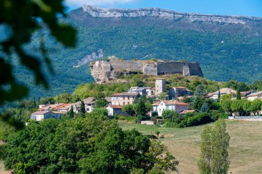 Distant view of the old village of Mison, France, surrounded by hills, with its medieval castle, located in the French department of Alpes-de-Haute-Provence