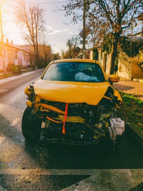 Sarı bir araba trafik kazasında kaza yapmış güneşli bir sonbahar sabahında şehir caddesinde duruyor.