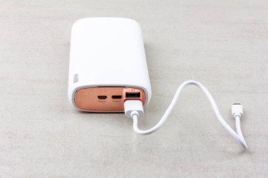 Gri arka planda akıllı telefonları ve çeşitli dijital cihazları şarj etmek için beyaz enerji bankası