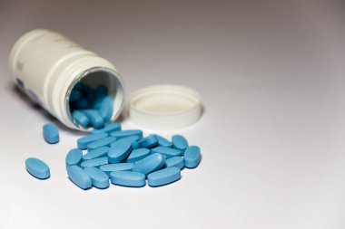 Açık plastik şişeyi kapat ve beyaz arka planda bir sürü mavi ereksiyon hapı var..