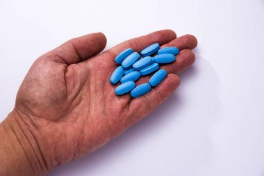 Erkek eli mavi hapları gösteriyor.