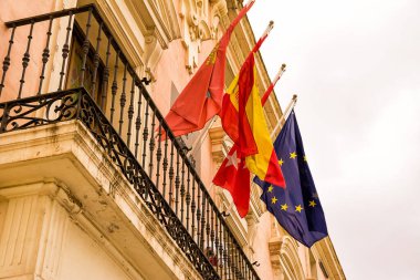 Spanish flag flanked by that of the city of Alcala of Henares, the province of Madrid and Europe