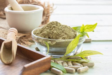 Andrographis, cam bardakta toz, çuvalda beyaz bardak, kapsüller, yapraklar, tahta tabak, kaşık ve çuval, eski ahşap arka planda..