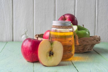 Şişedeki elma suyu, sağlıklı içecek, sepetteki kırmızı ve yeşil elma meyveleri ahşap zeminde, kopyalama alanı olan organik yiyecekler..