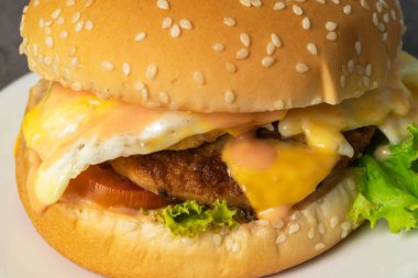 Peynirli tavuk burger ve beyaz çay tabağında marul..