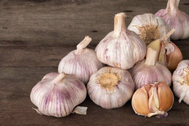 Sarımsak soğanları (Allium sativum L.) eski ahşap arka planda. Sarımsak kalp hastalığını önler ve akut kalp yetmezliği riskini azaltır..