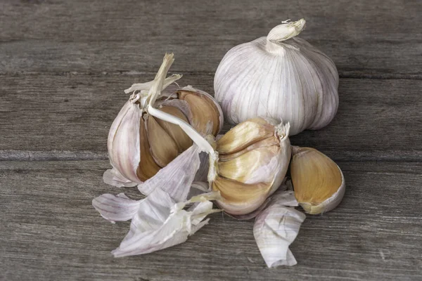 Garlic bulbs ( Allium sativum L.) and garlic cloves on old wooden background. Garlic helps reduce cholesterol and blood sugar levels.