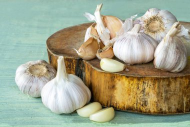 Garlic bulbs ( Allium sativum L.), garlic cloves on cutting board and on old wooden background. Garlic helps strengthens the body's immune system.