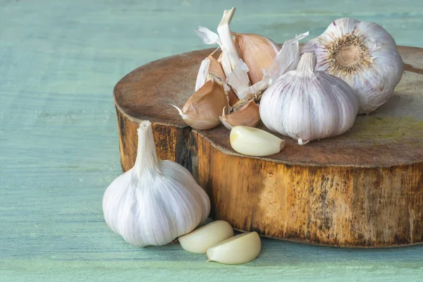 Garlic bulbs ( Allium sativum L.), garlic cloves on cutting board and on old wooden background. Garlic helps strengthens the body\'s immune system.