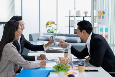 Genç Asyalı girişimciler iş ağlarıyla uzaktan sohbet ederken akıllı telefonlarına bakarlar..