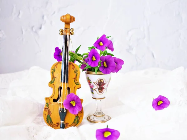 Violet Flowers Violin Toy White Embroidered Cloth Background Calibrachoa Petunia — Stock Photo, Image