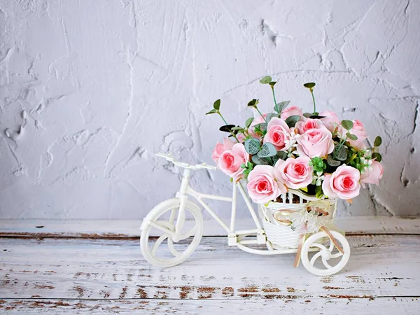 Yapay pembe gül çiçekleri bisiklet oyuncağında masa buketi üstünde bisiklet yumuşak tonlu şenlik desenli arka plan çimento duvar kâğıdı fotokopi alanı Sevgililer Günü romantik aşk kartı 