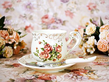 Antique cup of tea with saucer ,yellow orange rose flowers background ,porcelain vintage style ,old English coffee cup still life for wallpaper ,romance roses backgrounds 