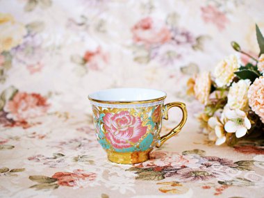 Antique cup of tea with saucer ,yellow orange rose flowers background ,porcelain vintage style ,old English coffee cup still life for wallpaper ,romance roses backgrounds 