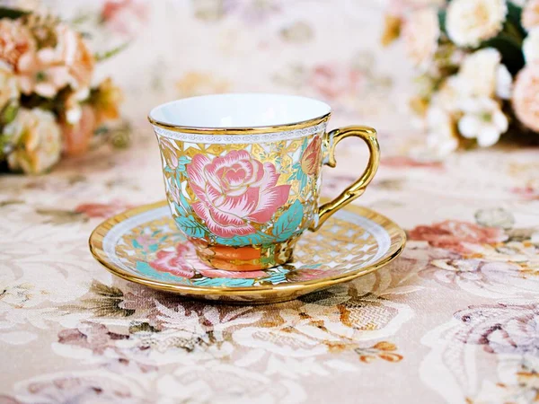 Antique cup of tea with saucer ,yellow orange rose flowers background ,porcelain vintage style ,old English coffee cup still life for wallpaper ,romance roses backgrounds 